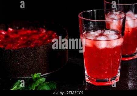 Composizione sorprendente con cheesecake alla fragola e bevanda alla fragola con rosmarino. Solo una parte della cheesecake a fuoco e una particella di un bicchiere di d Foto Stock