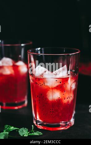 Composizione sorprendente con cheesecake alla fragola e bevanda alla fragola con rosmarino. Solo una parte della cheesecake a fuoco e una particella di un bicchiere di d Foto Stock