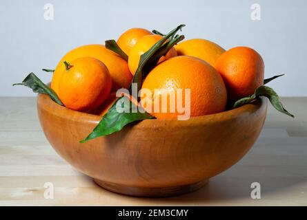 Alcune arance in un cesto su una superficie di legno Foto Stock