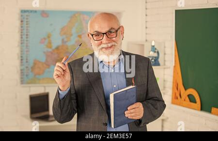 Docente esperto. Insegnante maturo godere di insegnamento. Condivisione delle conoscenze. Ottenere certificazioni per programmi specifici. Insegnante di uomo intelligente senior alla lavagna. Insegnante di vecchia generazione di scuola. Foto Stock