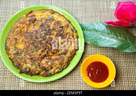 Popolare ricetta di Masala Omelet in stile nepalese indiano servita su piatto con ketchup di pomodoro. Foto Stock