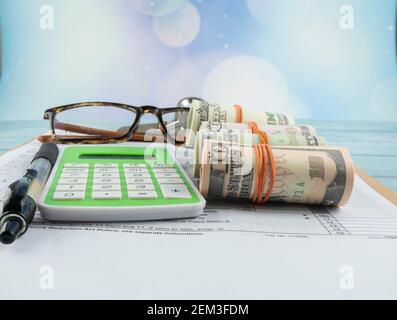 Concetto di riempimento delle imposte - ‘tempo di imposta’, denaro falso, e una calcolatrice con la metà del modulo US IRS 1040. Foto Stock