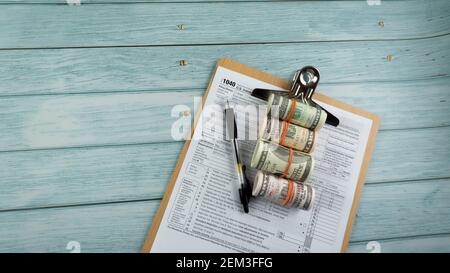 Concetto di riempimento delle tasse - ‘tempo di imposta’. Denaro falso, penna, con la metà del modulo US IRS 1040. Foto Stock