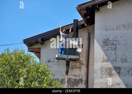 Zrenjanin, Serbia, 13 agosto 2020. I lavoratori con un autocarro speciale stanno riparando il tetto di un edificio alto. Il lavoro sul tetto è molto pericoloso a causa dell'hei Foto Stock