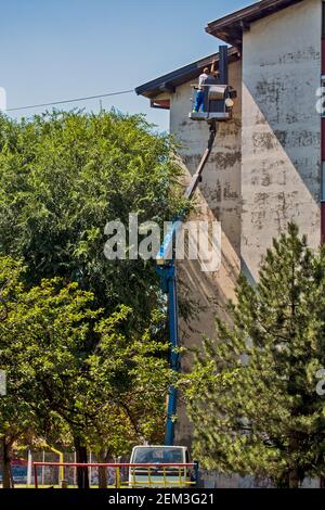 Zrenjanin, Serbia, 13 agosto 2020. I lavoratori con un autocarro speciale stanno riparando il tetto di un edificio alto. Il lavoro sul tetto è molto pericoloso a causa dell'hei Foto Stock