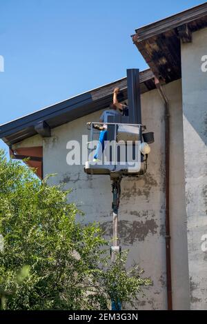 Zrenjanin, Serbia, 13 agosto 2020. I lavoratori con un autocarro speciale stanno riparando il tetto di un edificio alto. Il lavoro sul tetto è molto pericoloso a causa dell'hei Foto Stock