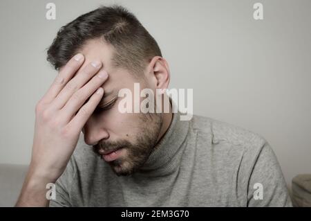 Ritratto di un giovane che tocca la fronte per mettere a fuoco o a causa di un mal di testa Foto Stock