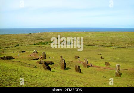 Gruppo di visitatori che visita il sito di abbandonate statue giganti di Moai incompiuta al vulcano Rano Raraku con l'oceano Pacifico sullo sfondo, Isola di Pasqua, C. Foto Stock