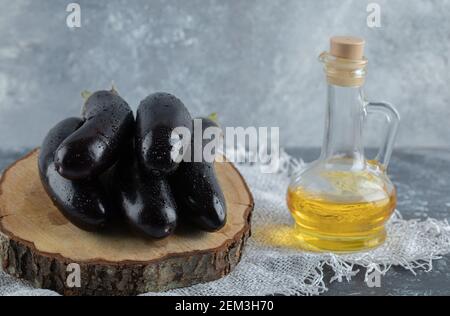 Melanzane viola fresche su tavola di legno e bottiglia d'olio Foto Stock