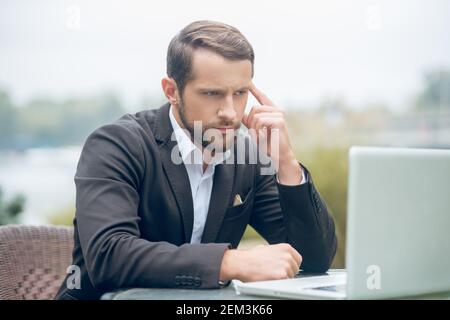 Attraente uomo di successo che guarda seriamente lo schermo del laptop Foto Stock