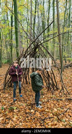 Ragazzi in una capanna fatta di tronchi e rami in un parco giochi forestale, Germania, Nord Reno-Westfalia Foto Stock