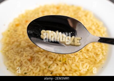 Alfabeto lettere zuppa con lotta sul cucchiaio, immediato facile fast food a causa della povertà Foto Stock