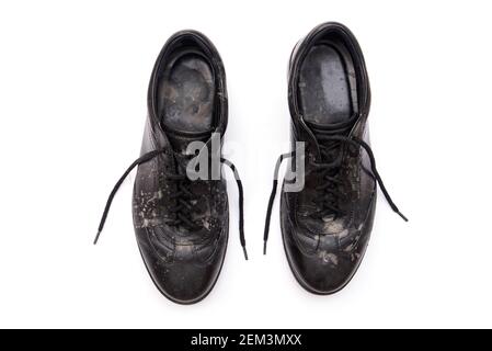 Scarpe nere sporche e polverose con macchie sporche dopo l'isolamento dalla pioggia su bianco Foto Stock