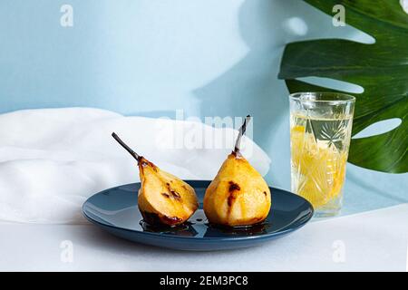 Estate ancora vita pere cotte in sciroppo di caramello e acqua con limone. Concetto di cibo sano. Composizione moderna con le lunghe ombre della foglia di palma monstera, mo Foto Stock