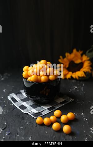 Prugne gialle su sfondo nero. Ingredienti per una marmellata. Fotografia alimentare. Immagine verticale. Girasole giallo, concetto autunnale, Foto Stock