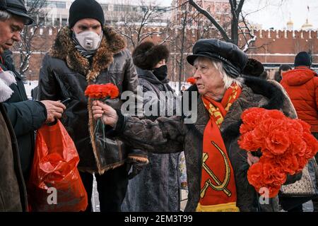 Mosca, Russia. 23 Feb 2021. Un anziano comunista distribuisce garofani rossi ai suoi compagni durante il rally.il Partito Comunista della Federazione Russa ha riunito martedì attivisti del fronte di sinistra, il Lenin Komsomol, il movimento per il nuovo socialismo, L'Unione delle donne "speranza della Russia" e altre organizzazioni correlate per deporre fiori alla Tomba del Milite Ignoto nel centro di Mosca. Credit: SOPA Images Limited/Alamy Live News Foto Stock