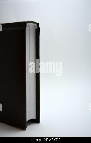 Un piccolo libro, un notebook, un diario in una copertina marrone scuro si trova su uno sfondo bianco con un'illuminazione interessante. Foto Stock