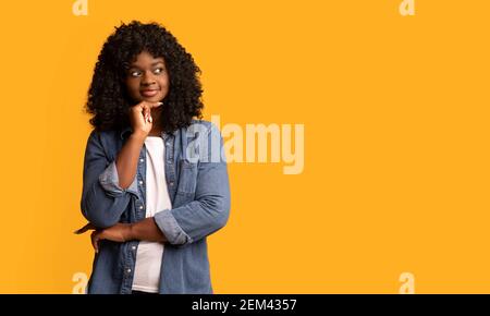 Eccitata giovane donna afroamericana che guarda lo spazio vuoto e sorride Foto Stock