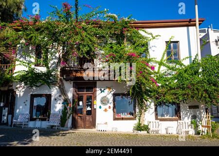 Kalkan, Turchia - 4 novembre 2020: Antico edificio bianco e in legno con alberi di bougainvillea nelle vicinanze Foto Stock