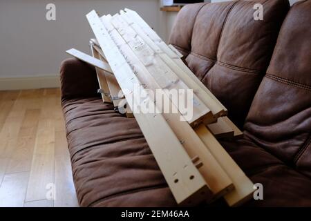 Tavole di legno da un telaio di letto sulla cima di a. divano marrone in una casa Foto Stock