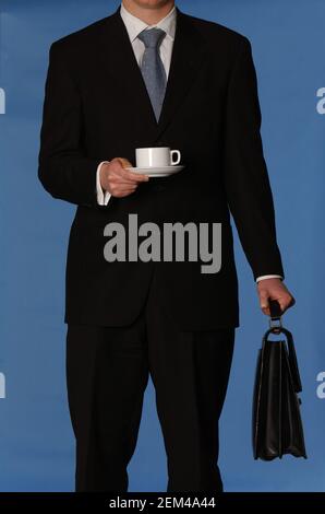 Uomo d'affari bianco senza volto in un vestito nero con un cravatta blu con valigetta in pelle nera e tazza da tè su sfondo blu Foto Stock