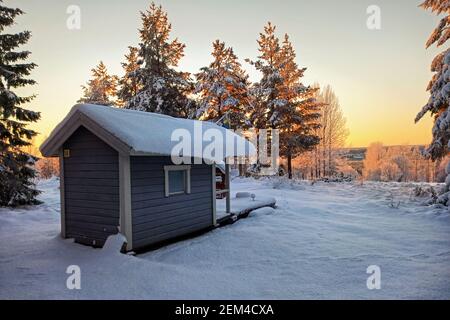 Piccola capanna svedese al tramonto e sulla neve. Foto Stock