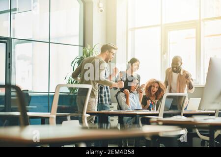 Giovani energici che celebrano il successo del loro progetto sul lavoro Foto Stock