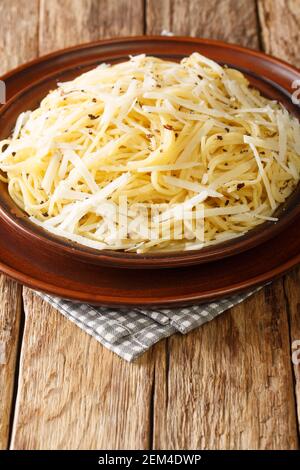 Spaghetti Cacio e Pepe Ricetta primo piano nel piatto sul tavolo. Verticale Foto Stock