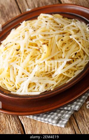 Cacio e pepe Pasta con formaggio e pepe in primo piano nel piatto sul tavolo. Verticale Foto Stock