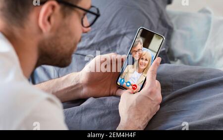 Uomo che effettua videochiamate con i genitori utilizzando lo smartphone Foto Stock