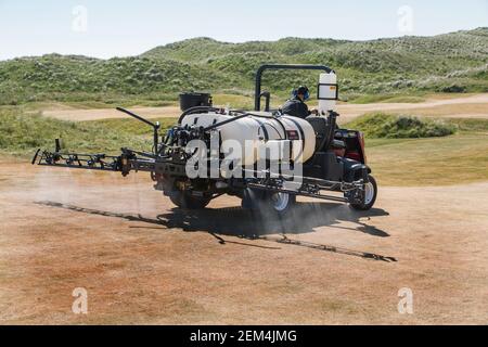 Un greenkeeper che usa un moderno spruzzatore sul campo da golf Foto Stock