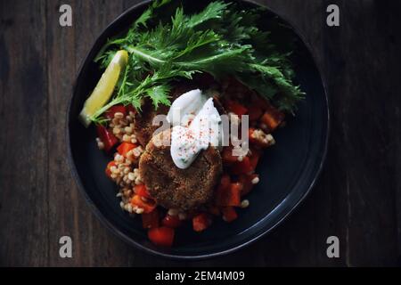 Salmone fishcakes con oat e insalata su un tavolo di legno Foto Stock