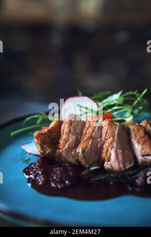 Confit di anatra con insalata , mela cotta e la salsa di lamponi servita su un tavolo di legno Foto Stock