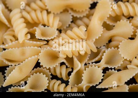 Tonde di farfalle crude e pasta di girandole su fondo nero Foto Stock