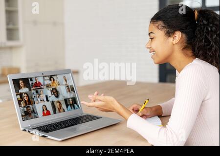 Una donna d'affari biraciale di successo con una coda di pioli, che parla su un laptop, un ufficio domestico, che lavora a distanza, che spiega una strategia, freelance, discutere un nuovo progetto con il team, utilizzando il pensiero critico Foto Stock
