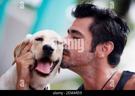 Primo piano di un uomo medio adulto che baciava un cane Foto Stock