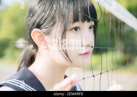 Ritratto di bella ragazza giapponese alta asiatica uniforme cercando con rete su sfondo verde Foto Stock