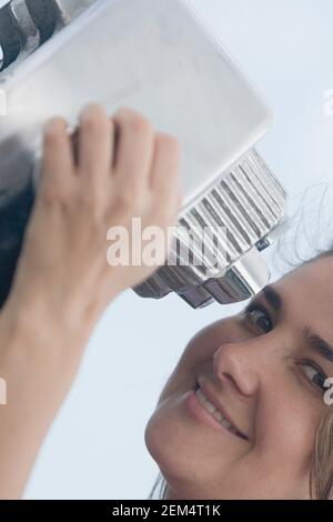 Ritratto di una donna mid adult che tiene un paio di binocoli a gettoni e sorridenti Foto Stock