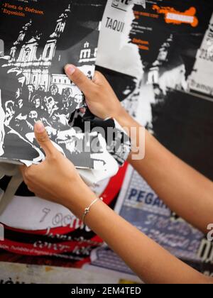 Primo piano delle mani di una donna che strappano un poster Foto Stock