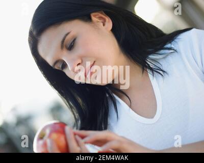 Close-up di una giovane donna in possesso di un apple e pensare Foto Stock
