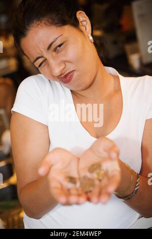 Ritratto di una donna mid adulta che mostra monete e la fabbricazione una faccia Foto Stock