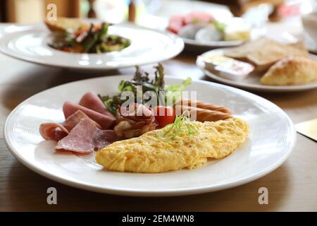 Set colazione frittata con salsicce e pancetta insalata su uno sfondo di legno Foto Stock