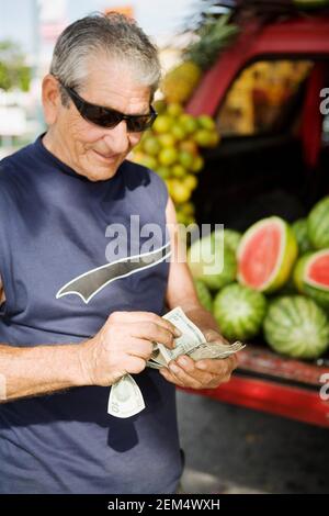 Primo piano di un uomo anziano che conta le fatture del dollaro americano Foto Stock