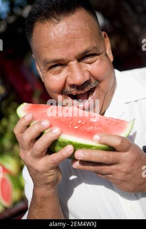Ritratto di un uomo maturo che tiene una fetta di A. cocomero e aspetto allegro Foto Stock