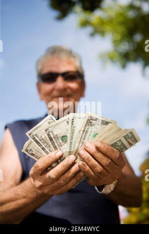 Primo piano di un uomo anziano che conta le fatture del dollaro americano Foto Stock