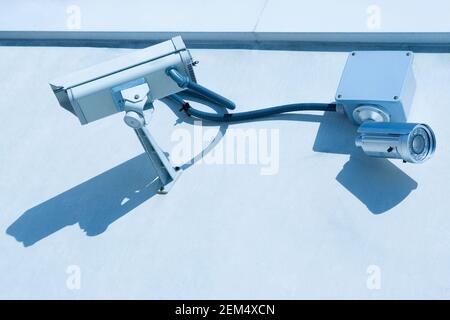 Vista a basso angolo di due telecamere di sicurezza sulla parete Foto Stock