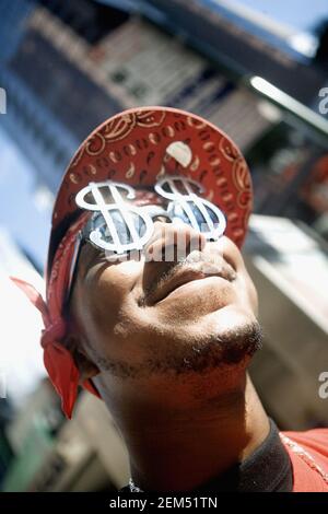 Primo piano di un giovane uomo che indossa occhiali da sole con simbolo del dollaro, New York City, New York state, USA Foto Stock