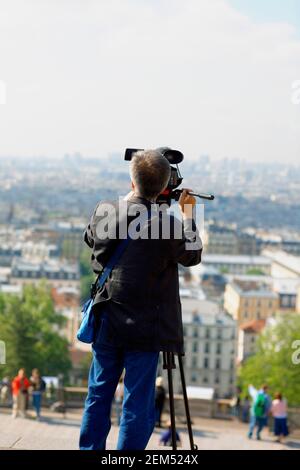 Vista posteriore di un uomo che guarda una città attraverso un paio di binocoli, Parigi, Francia Foto Stock