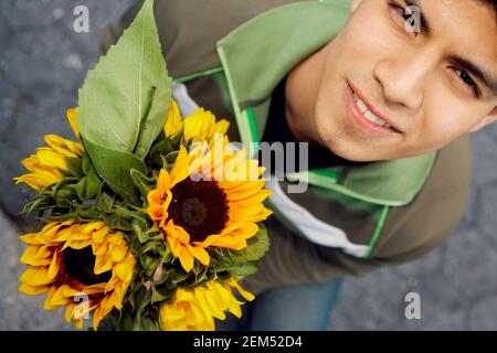 Ritratto di un giovane che tiene girasoli Foto Stock
