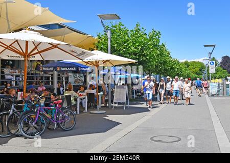 Konstanz, Germania - 2020 luglio: Strada turistica con caffè all'aperto e la gente al porto sul lago di Costanza nella soleggiata giornata estiva Foto Stock